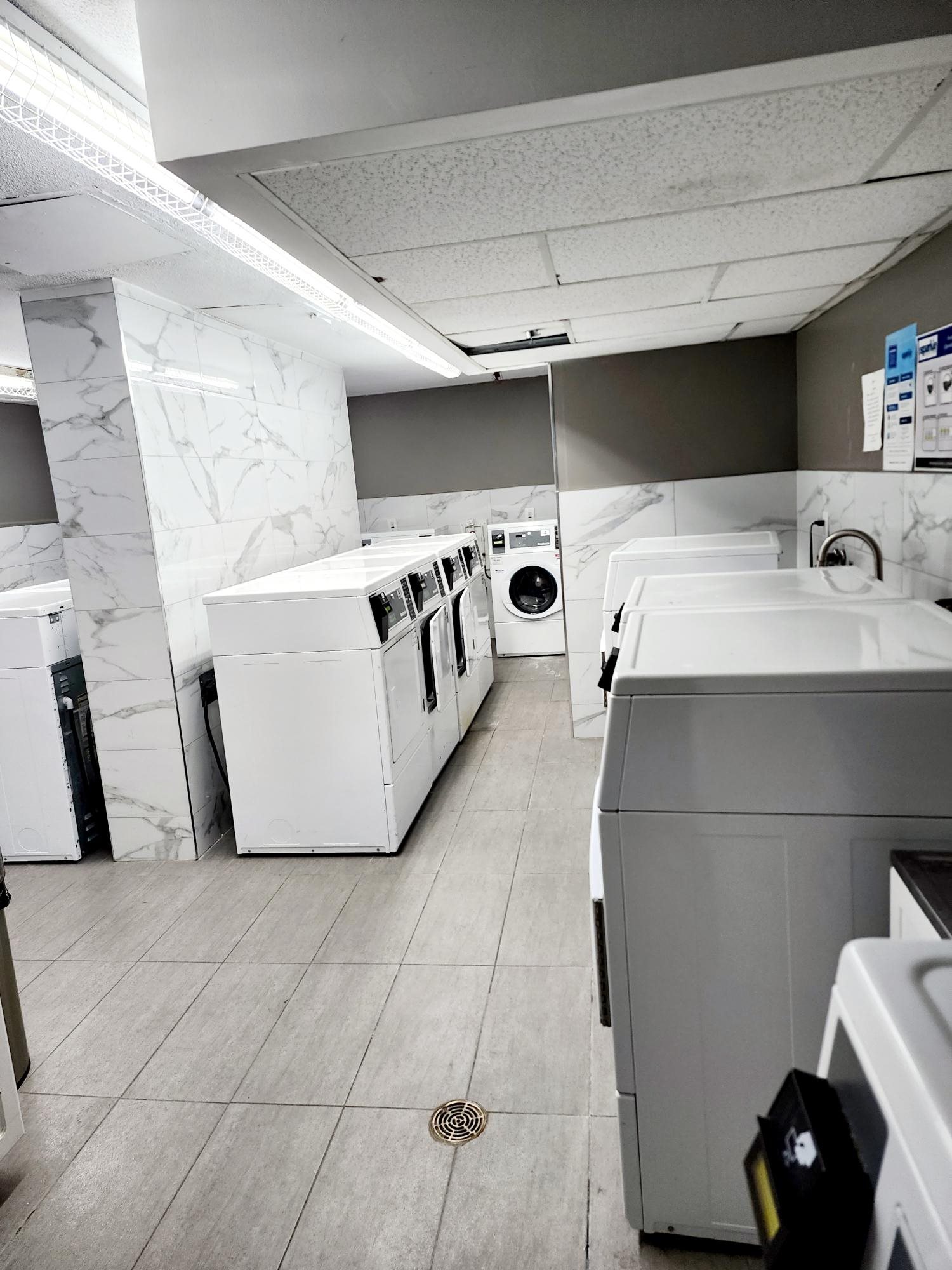 A laundromat with a washer and dryer on the left and a washer and dryer on the right.